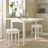 Small white kitchen set with foldable table and stools, perfect for limited spaces.