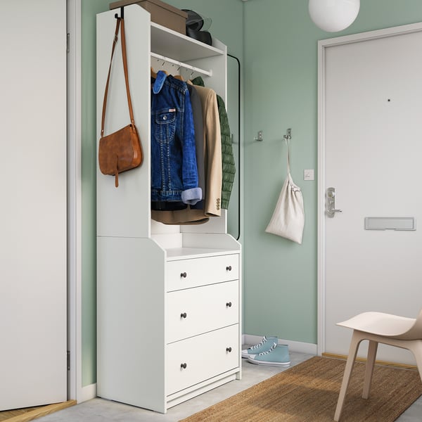 Modern white HAUGA wardrobe with clothes and bag; sleek, minimalist design.
