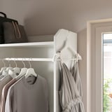 Closet with gray clothes hangers and shelf with bag.