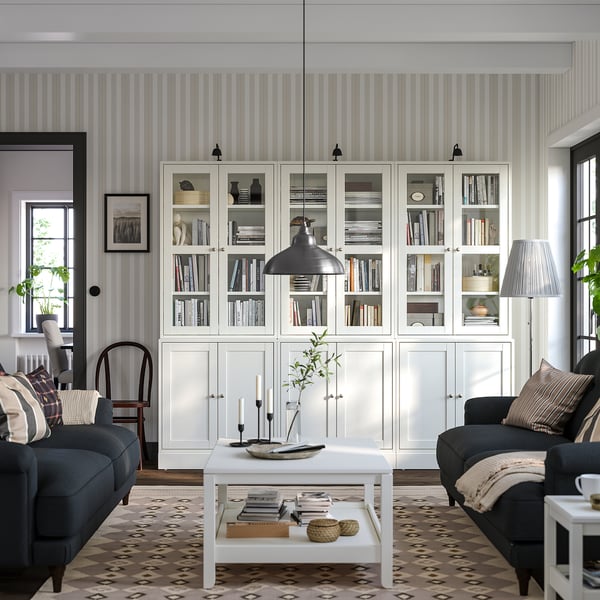 New living room: HAVSTA white pine bookshelves, gray couches, black pendant light, patterned rug, coffee table with decor and pillows.