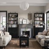 Modern living room with HAVSTA black bookshelf, cream sofas, grey rug, fireplace.