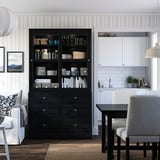 Modern living room with black HAVSTA cabinet, glass doors, white kitchen, couch, chairs, dining table.