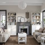 Modern living room with white HAVSTA storage units, light grey sofas, black-framed fireplace, and neutral decor.