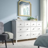 Calm bedroom with white HEMNES chest, large mirror, gray bed and chair. Wooden, six-drawer dresser dominates space.