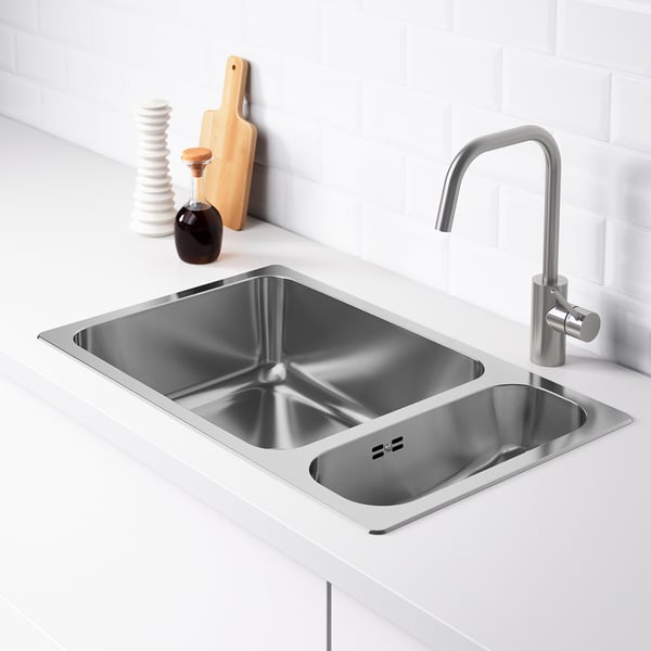 Double stainless steel kitchen sink with modern faucet on white countertop. Includes a large bowl and small bowl for versatile use.