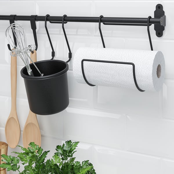 Black HULTARP rail mounts on white brick wall, holding black container with utensils and white paper towel roll.