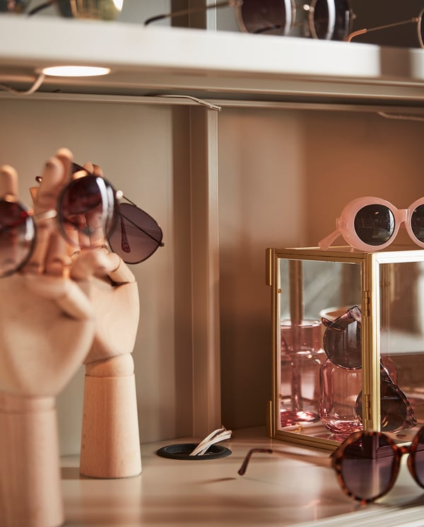Display of sleek sunglasses on golden stands and wooden mannequin, modern design.