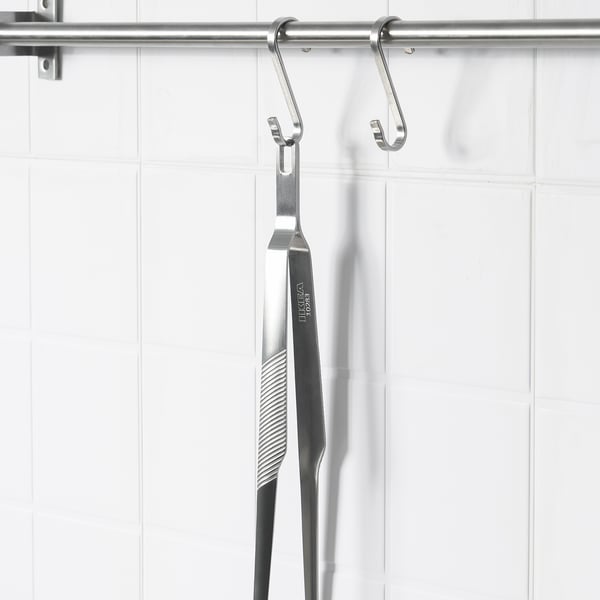 A pair of stainless steel kitchen tweezers hang from hooks, ideal for gripping and serving food.