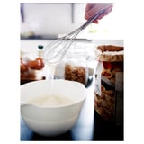 Hand mixing in bowl, whisk beside baked goods.