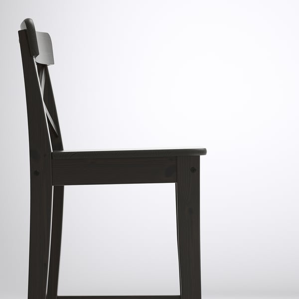 Black wooden chair side view, sleek design, solid pine construction.