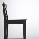Black wooden chair side view, sleek design, solid pine construction.