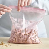 Person holds zippered bag with granola. Bag has colorful wave pattern, sealed shut.