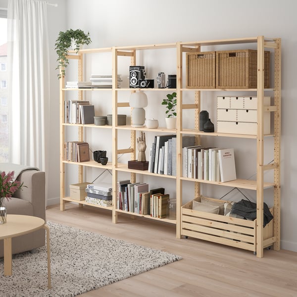 Natural wood IVAR shelving unit, filled with books, baskets, and decorative items. Tall, rectangular, fits well with large couch and rug.