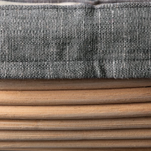 Close-up of light gray, woven fabric on wooden planks.