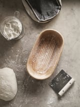 Bread basket, tools, rattan, dusted, scraper, cloth, floured surface.