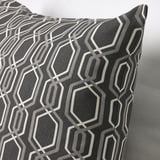 Geometric shapes in grey on textured cushion, modern design with precise stitching.