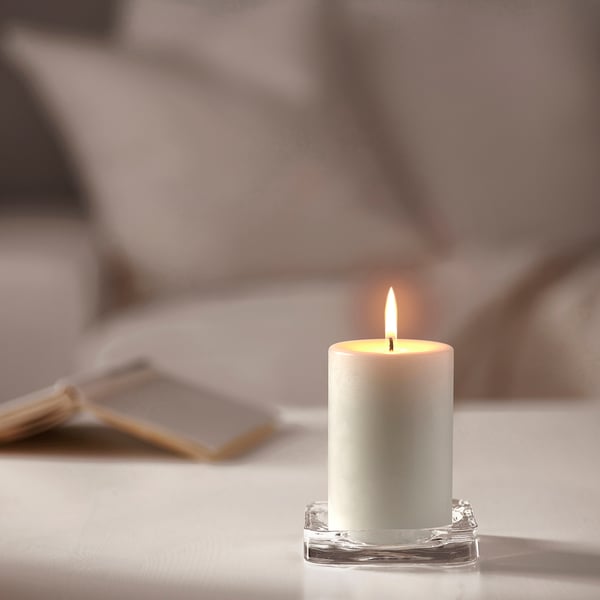White JUBLA candle in glass holder burns brightly. Small, clean design.
