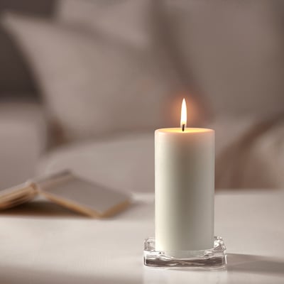 Informative a white JUBLA candle on a clear glass plate, showing detailed lace design as it burns.