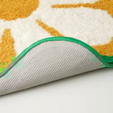 Thick, plush bath mat with large flower patterns, bordered in green, on soft backing.