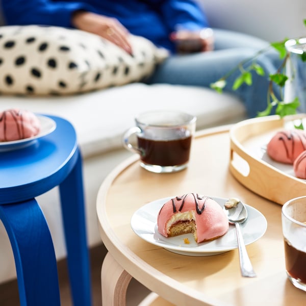 A cozy setup with pink cream cakes, coffee, and comfortable seating for socializing.