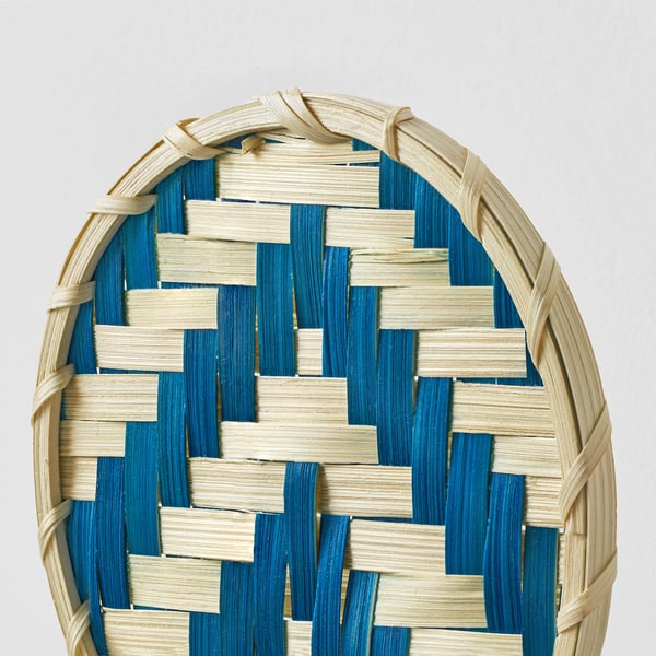 Interwoven bamboo wall art with natural and blue stripes. Crafted details visible, high-quality texture.