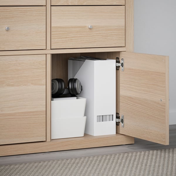 Light wood cabinet open with KALLAX shelves and white storage bins, showing home organization.