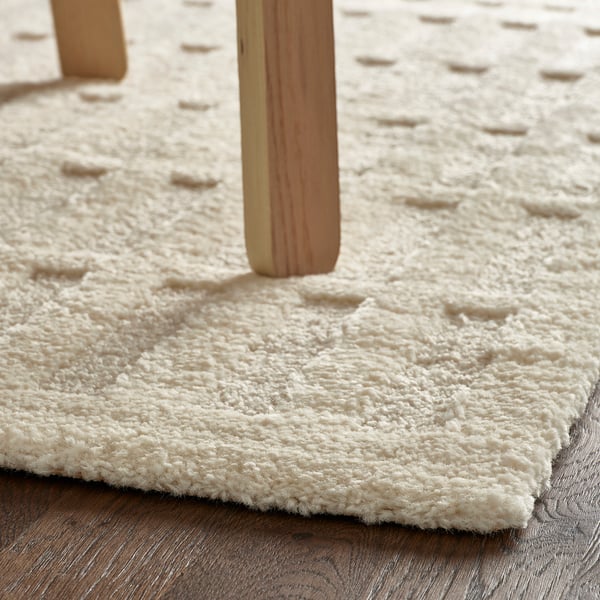 Wooden furniture legs on a textured, ivory-colored rug