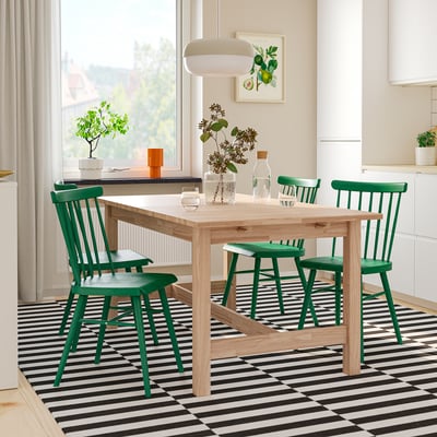Bright dining room with KARSKÄR table & green chairs. Table extends, chairs have spindle backs. Table central, chairs tucked in, floor patterned.