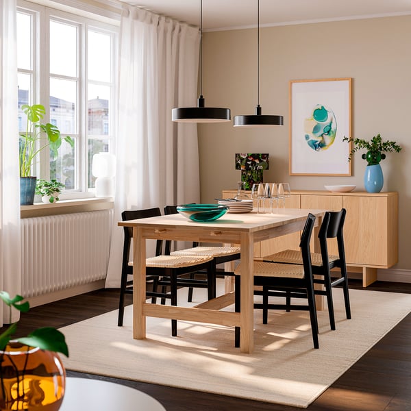 Bright dining area with KARSKÄR light wood table & black chairs, natural curtains, and modern decor. Table extends, seats 4-6, fits well in space.