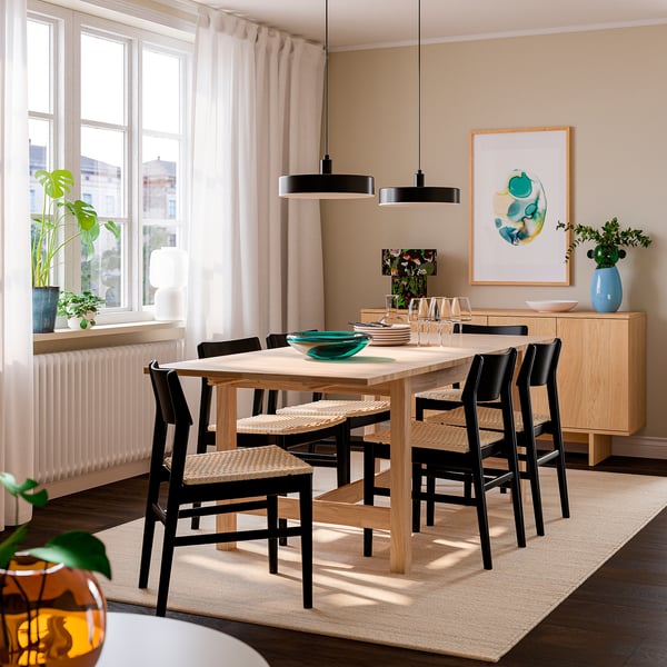Extendable dining table with 6 chairs, woven seats, abstract art above.