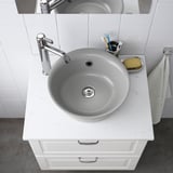 A modern marble sink with chrome faucet on quartz countertop, toothbrush holder, and soap dish.