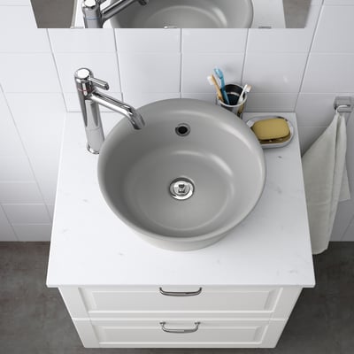 A modern marble sink with chrome faucet on quartz countertop, toothbrush holder, and soap dish.