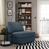 Modern blue KIVIK sofa-bed near large bookshelf, comfortable and compact for small spaces.