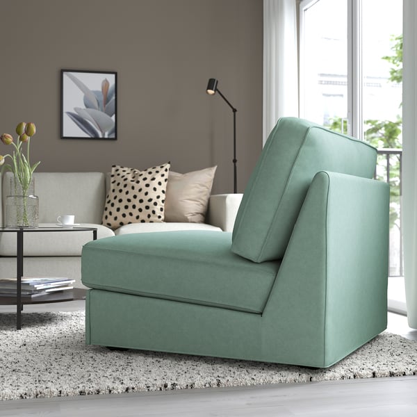 Modern living room with green KIVIK sofa-bed by window, coffee table & vase, polka dot bench.