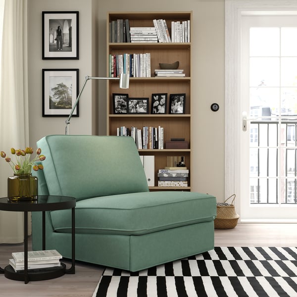 Cozy green KIVIK sofa-bed, compact for small spaces, by large bookcase and window.