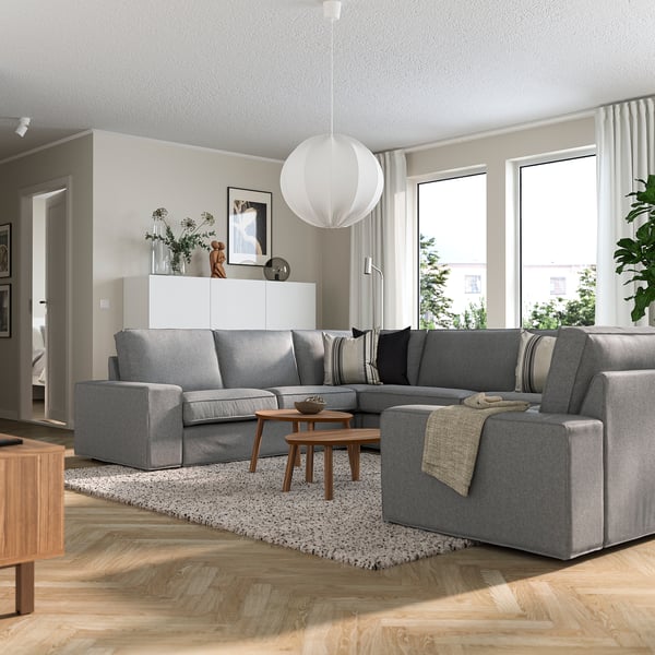 Modern living room with KIVIK sofa, sectional, coffee table, pendant lamp, and windows, accented with plants.