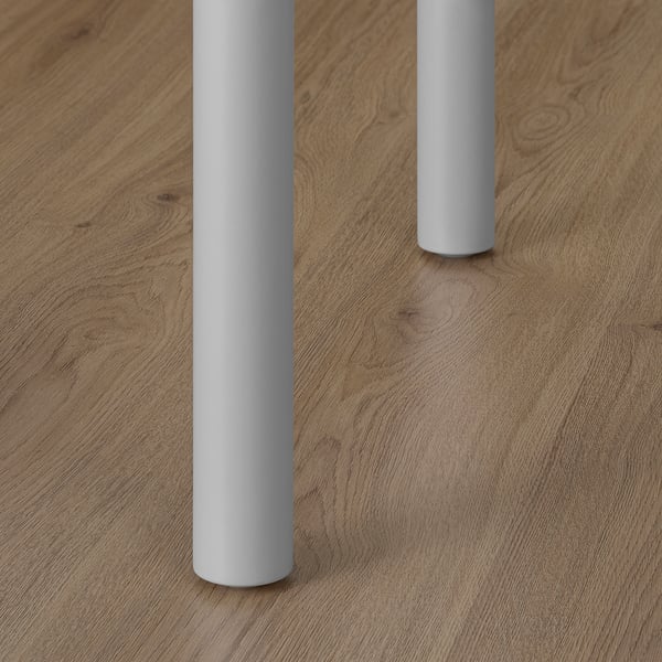 Modern minimalist desk with smooth, light wooden surface and rounded, light grey legs.