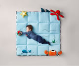 Baby on blue ocean-themed play mat with plush sea creature toys, including star, shark, crab, and octopus.