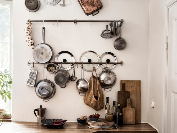 Kitchen wall with hanging pots, pans, and utensils for organized storage.
