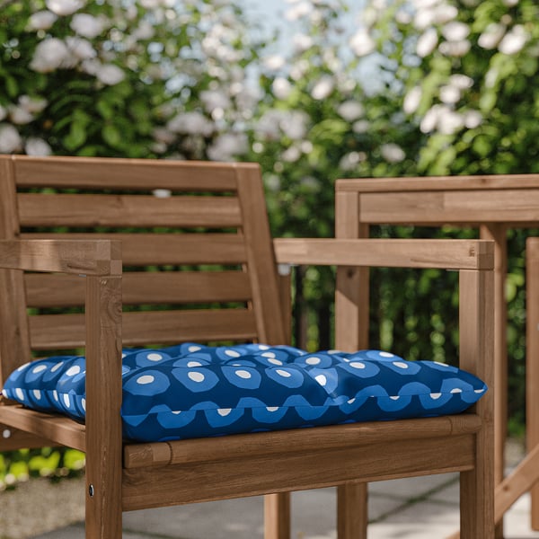 Two wooden chairs with blue patterned cushions outdoors.
