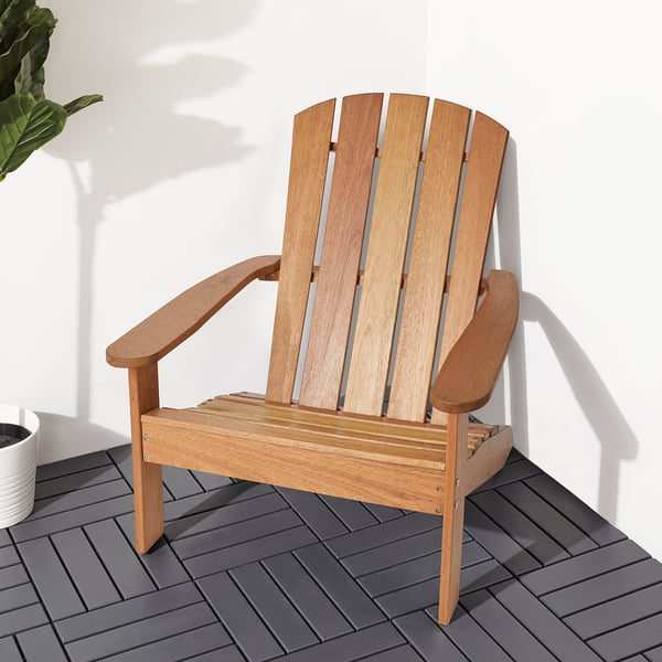 Wooden adirondack chair on grey deck, ideal for relaxation outdoors.