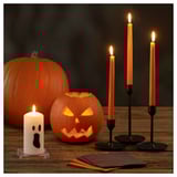 Halloween table decor: carved pumpkins, lit candles, folded napkins.