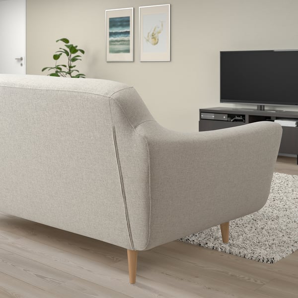 Modern light gray sofa with wooden legs, positioned against wall with artwork and a tv.