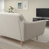 Modern light gray sofa with wooden legs, positioned against wall with artwork and a tv.