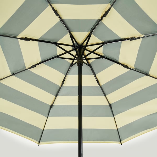 Close-up of open KNALLA umbrella. Cream and blue stripes on fabric, sturdy black frame visible from inside.