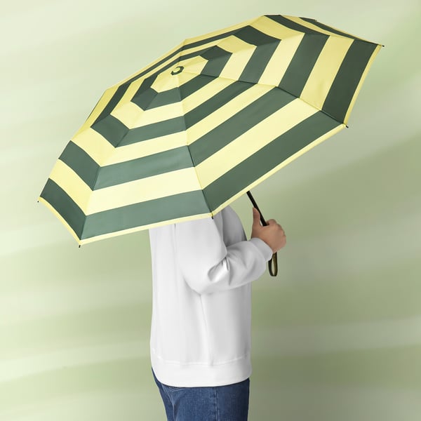Person holding a green and white striped umbrella with a black handle.