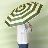 Person holding a green and white striped umbrella with a black handle.