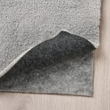 Rug corner visible with plush pile and non-slip underside showing.
