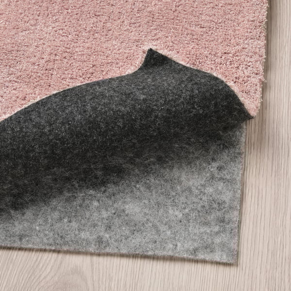 Rug with gray felt underlay on wooden floor.