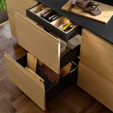Open kitchen drawer set showing organized utensils, cutlery, and pots, with sleek, dark finish.